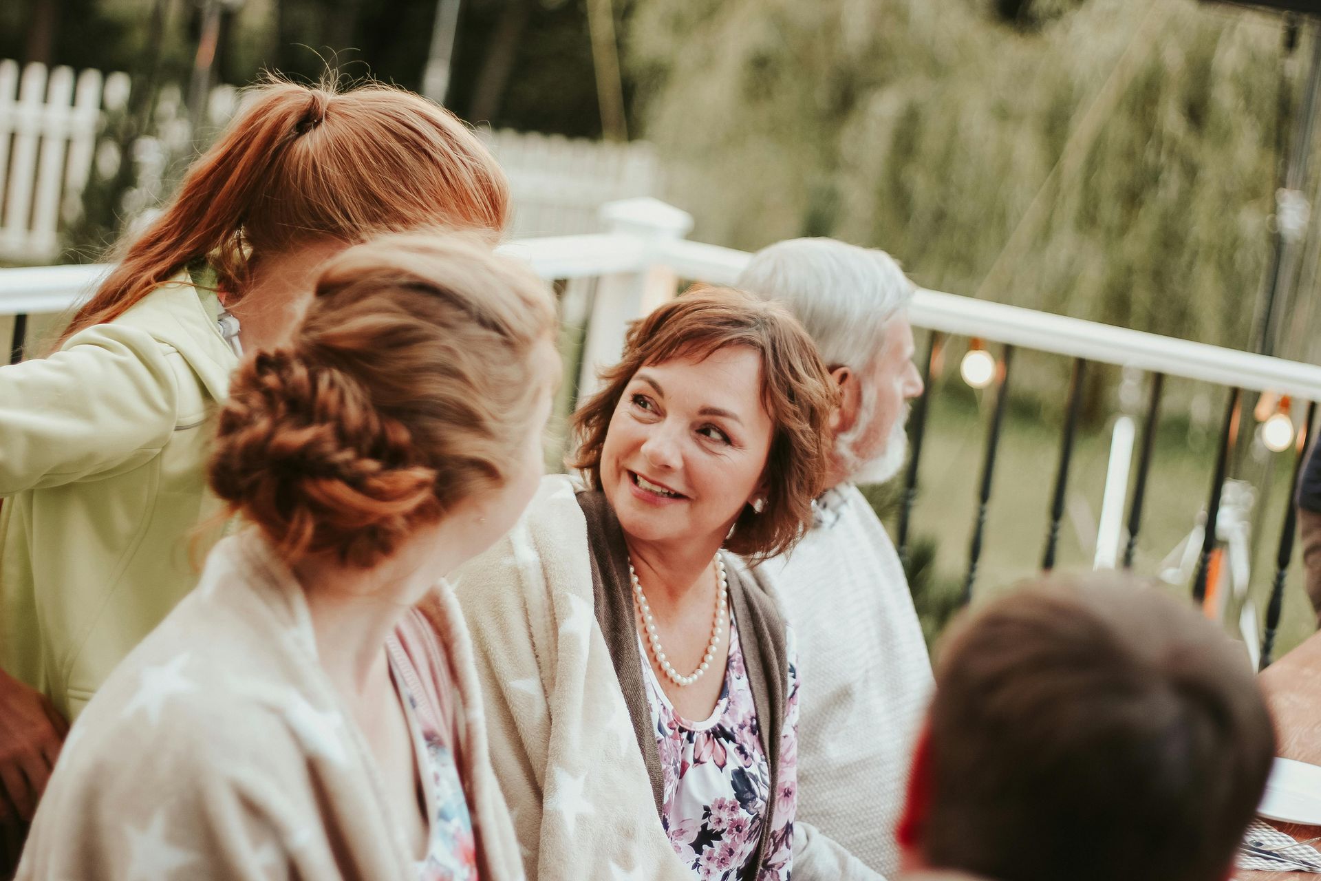 People gathered outdoors in conversation, with a woman in a patterned top centered in the group.